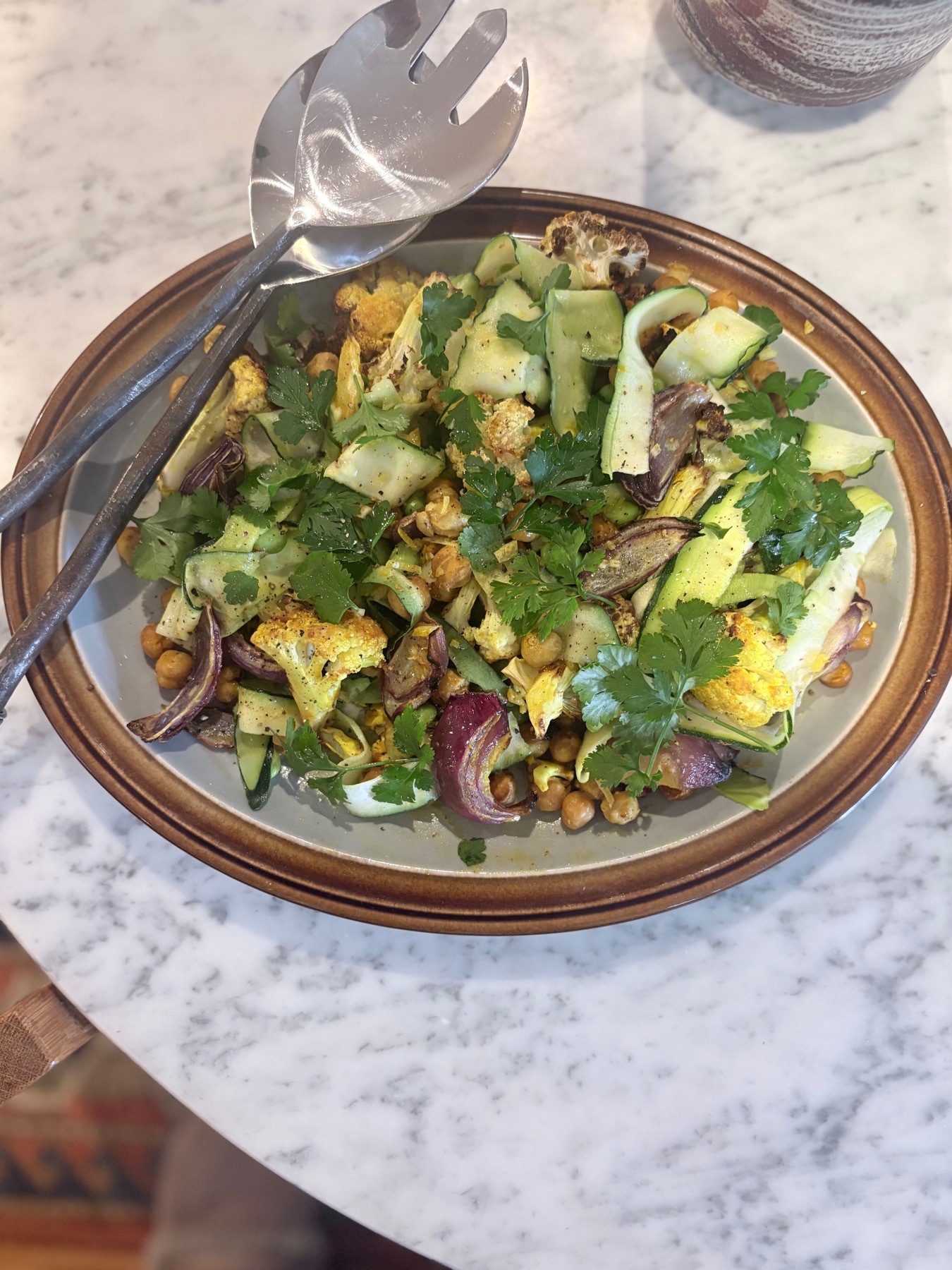 Miso roasted cauliflower with spiced chickpeas, red onion, zucchini ribbons and parsley on a plate
