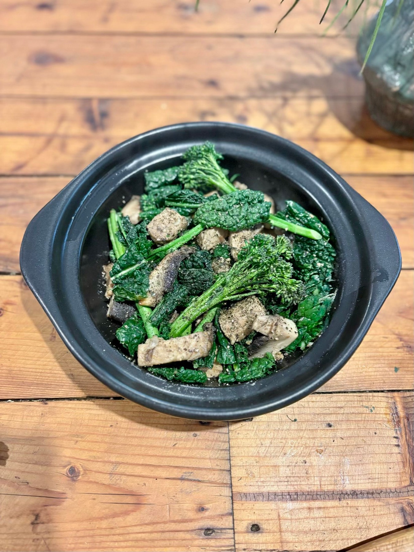 Tempeh, mushroom, cavolo nero and broccolini stir-fry served in a black bowl